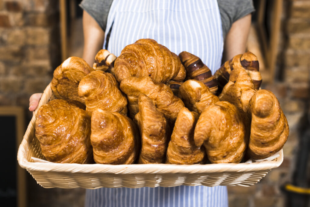 female baker s hand holding basket baked croissant